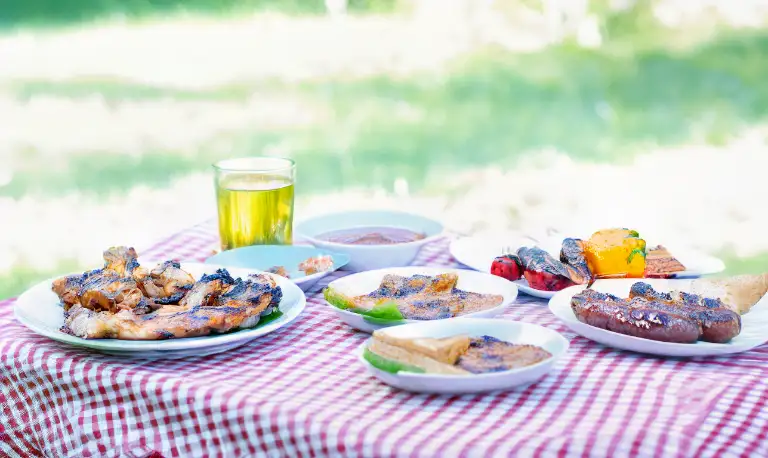 BBQ food on an alfresco dining table with red and white check table cloth in the garden