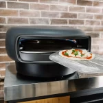 Inserting a pizza into an Everdure kiln pizza oven