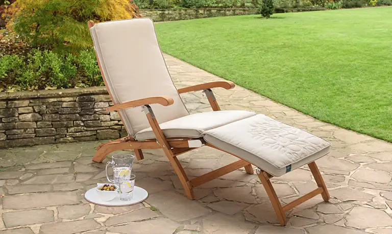 RHS steamer lounger chair on a stone paved patio in a traditional garden