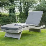 Universal Lounger in white wash with grey taupe cushions on the grass in a garden