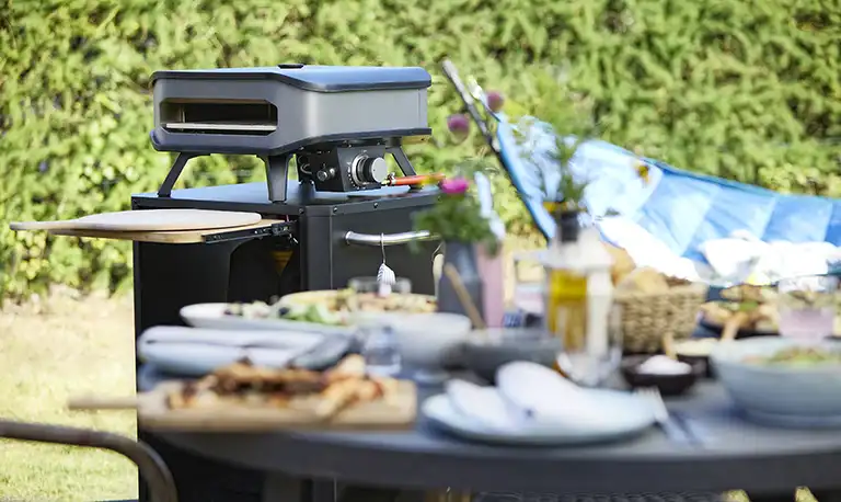 Food cooked in an outdoor kitchen area in a Cozze pizza oven