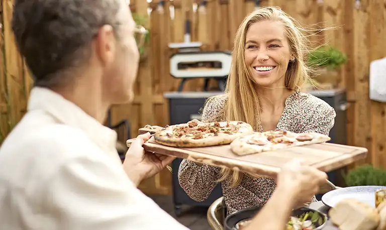 Friends enjoy pizza cooked in an outdoor kitchen